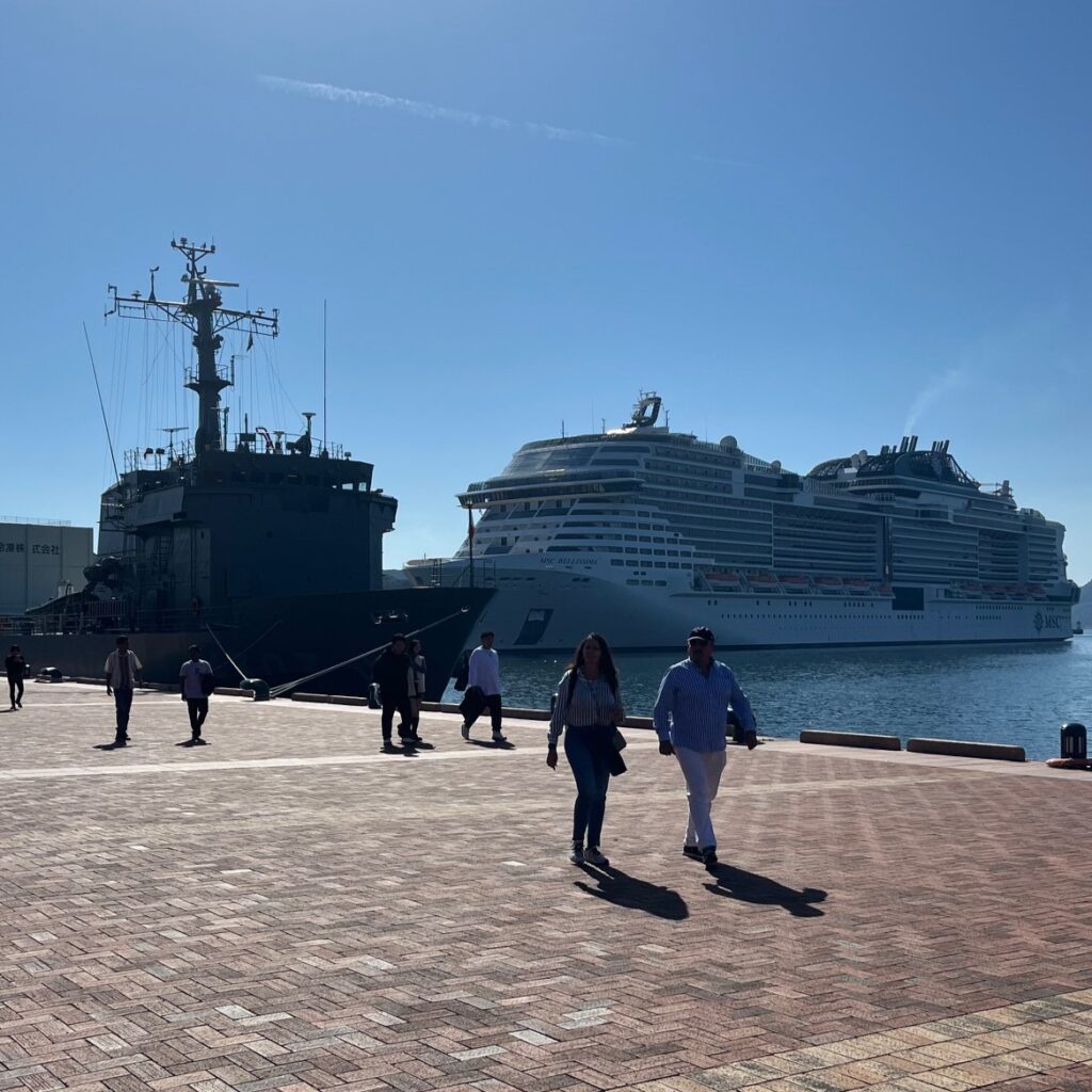 佐世保港に停泊している大型豪華客船と艦船、普段並ぶことのない船に港には多くの人で賑わっている