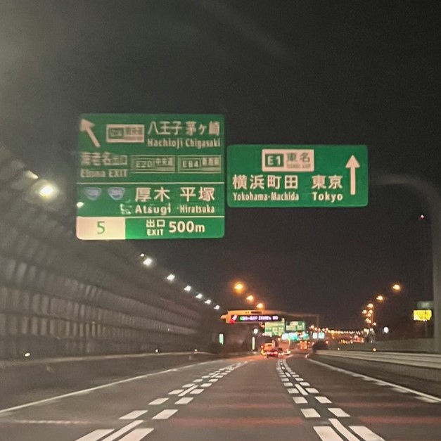 夜の東名高速の様子、大きな案内看板には東京と書かれている