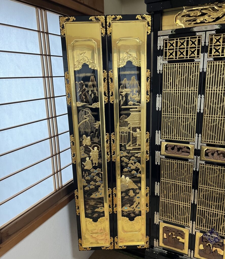 外扉内側の蒔絵。職人の伝統技術で、人物、お寺、松の木、山などが金箔で描かれている。