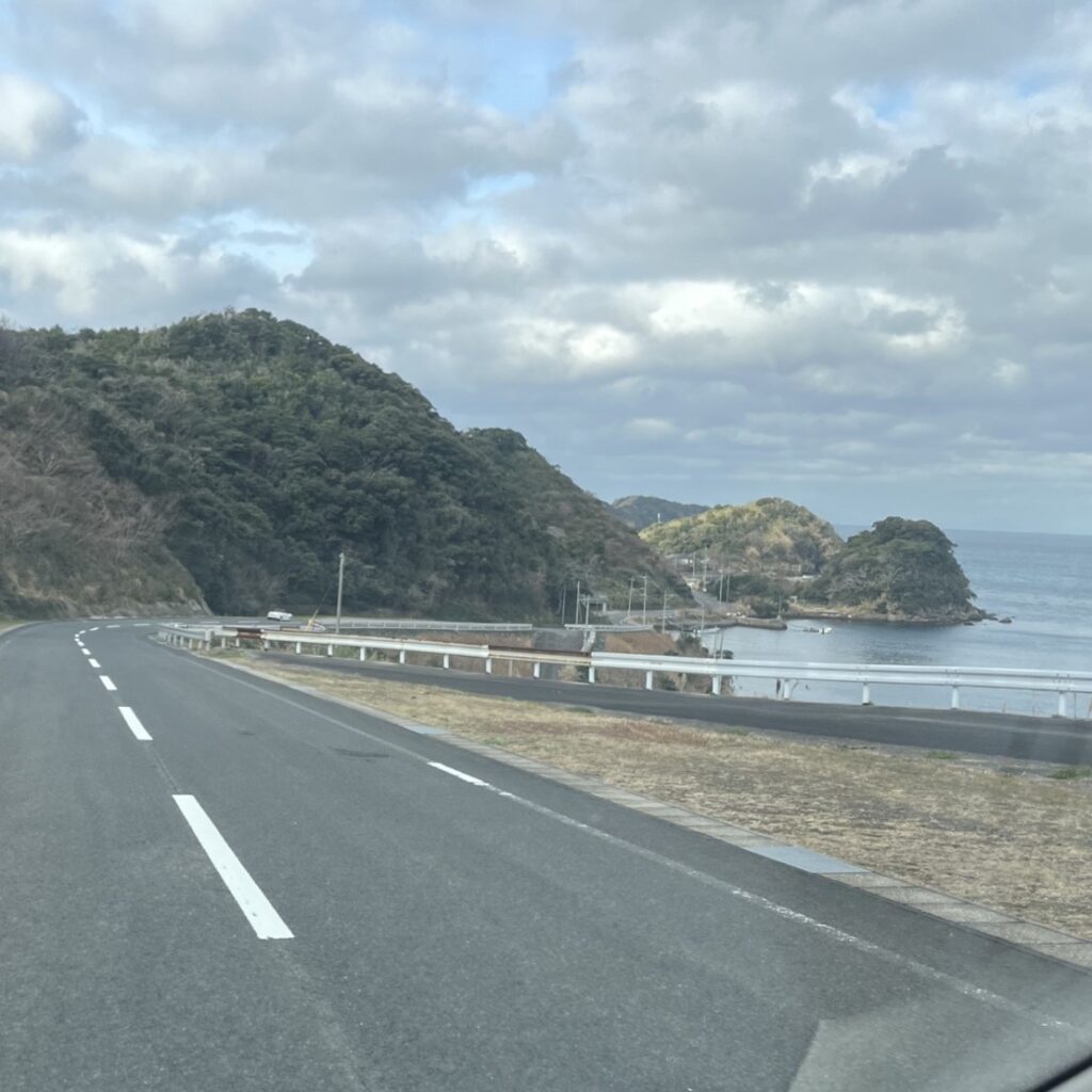 お仏壇を積み込み、福岡市南区へ向かう道、左側は小さな山、右側には海があり、海には小さな島がある