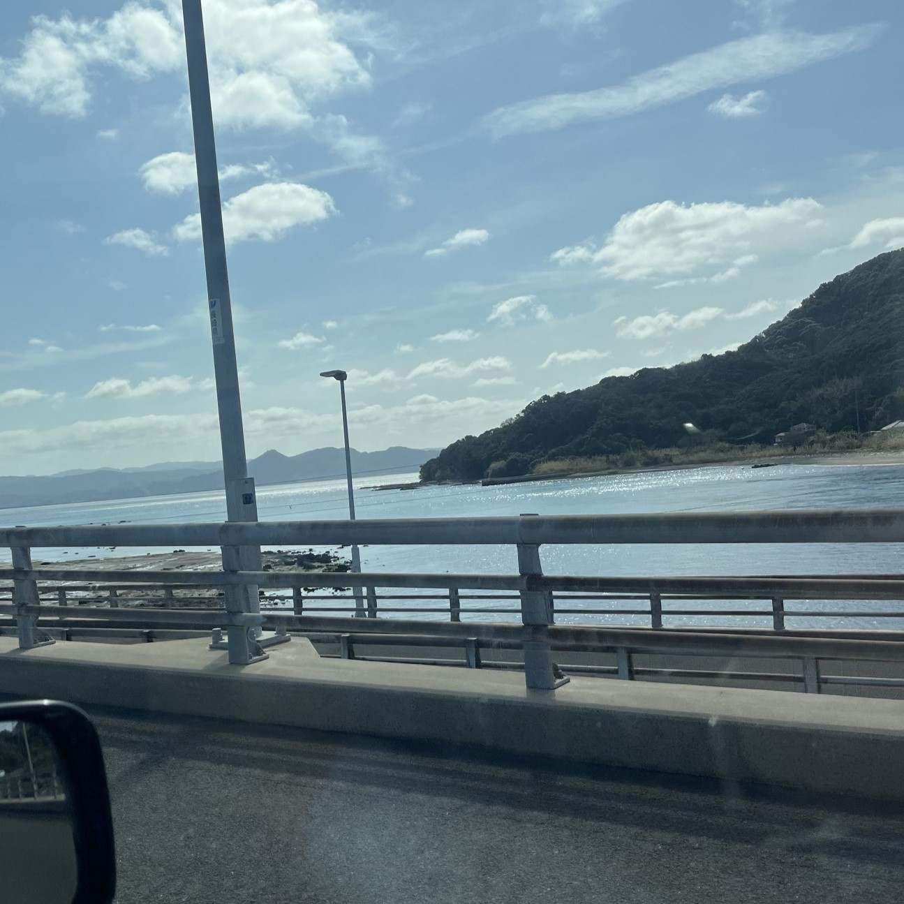 橋から見える青空と海、海には大きな島が広がっている