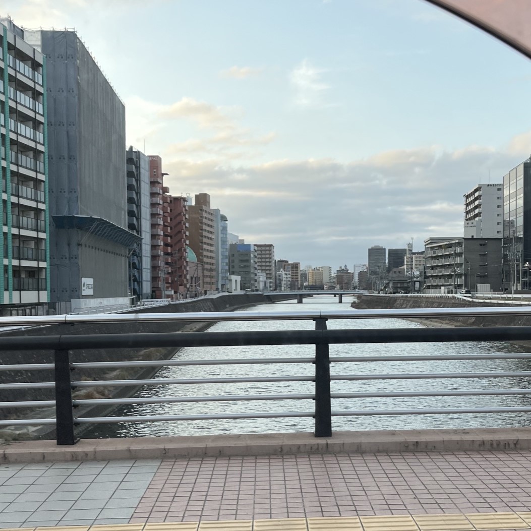 帰り道の福岡中心部の街並み川には何本も橋が架かっていて川の左右にはビル群が切れ目なく続いている