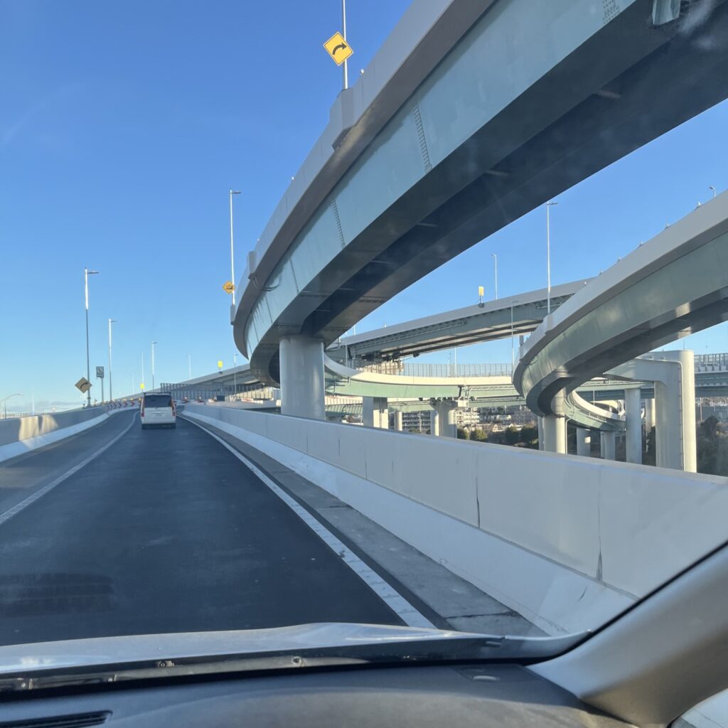 晴天の空の下、入り組んだ高速道路の合流地点で東京方面に向かう