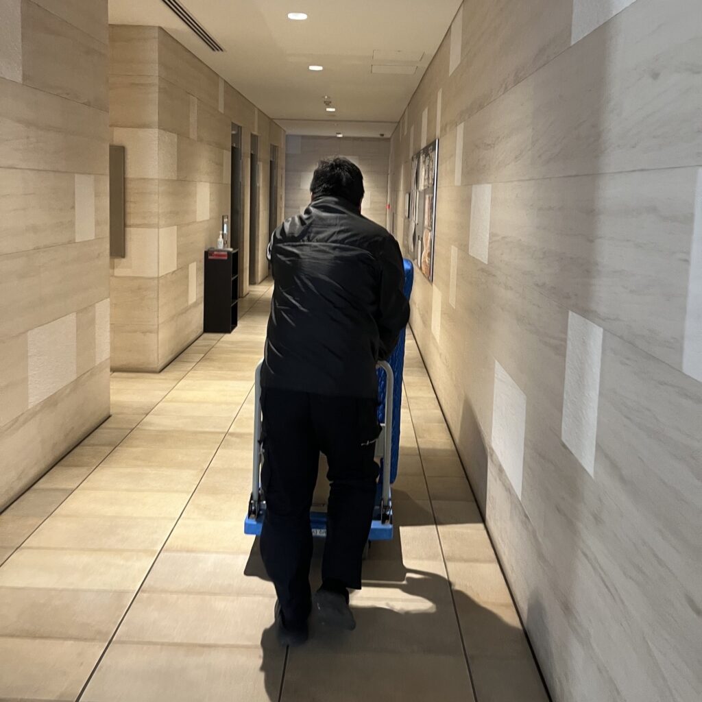 ロビーから少し狭くなる内部の通路でも台車に乗せたお仏壇を職人が慎重に運んでいる