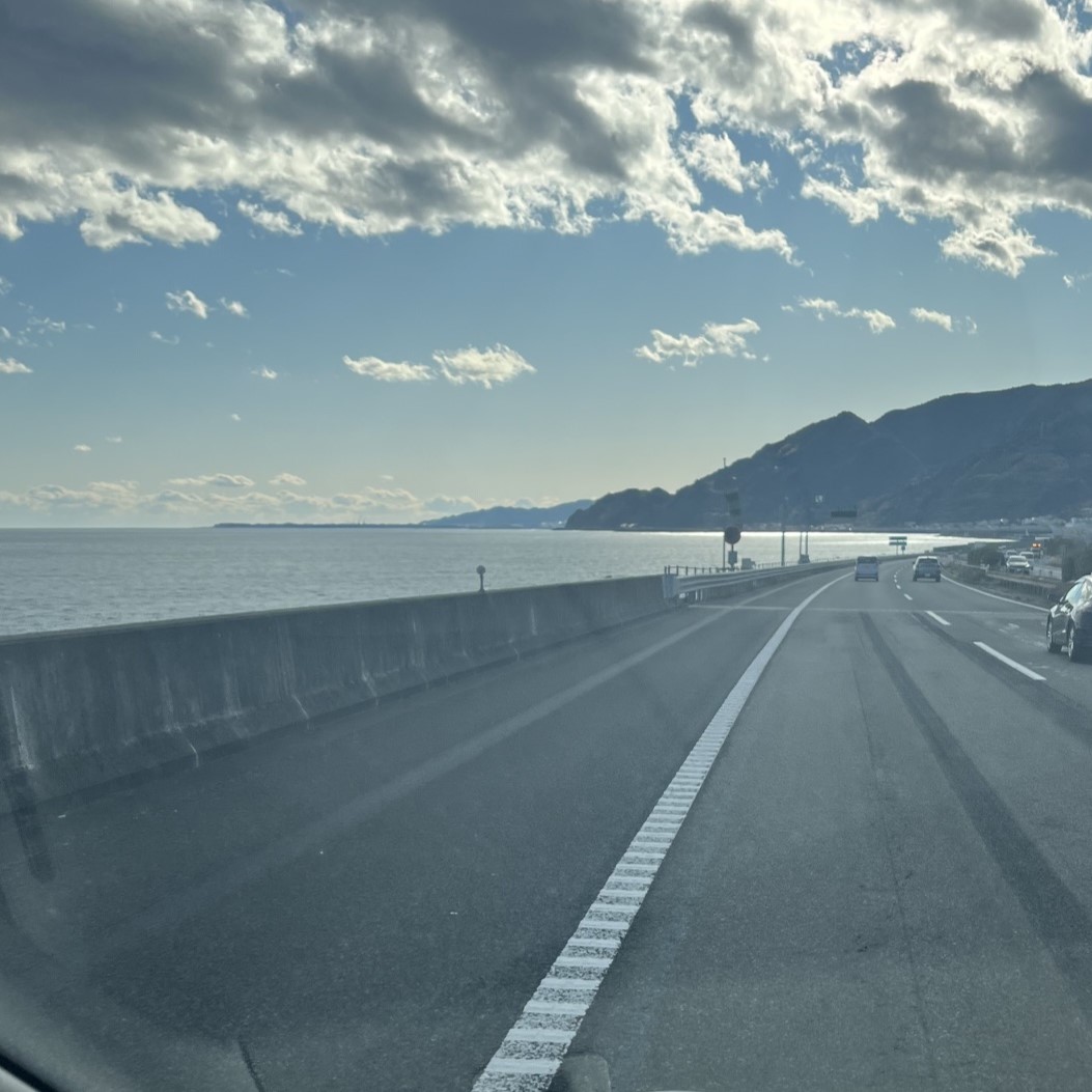 東名高速沿の駿河湾、広い道路のすく横に深い海と青空が広がっている。