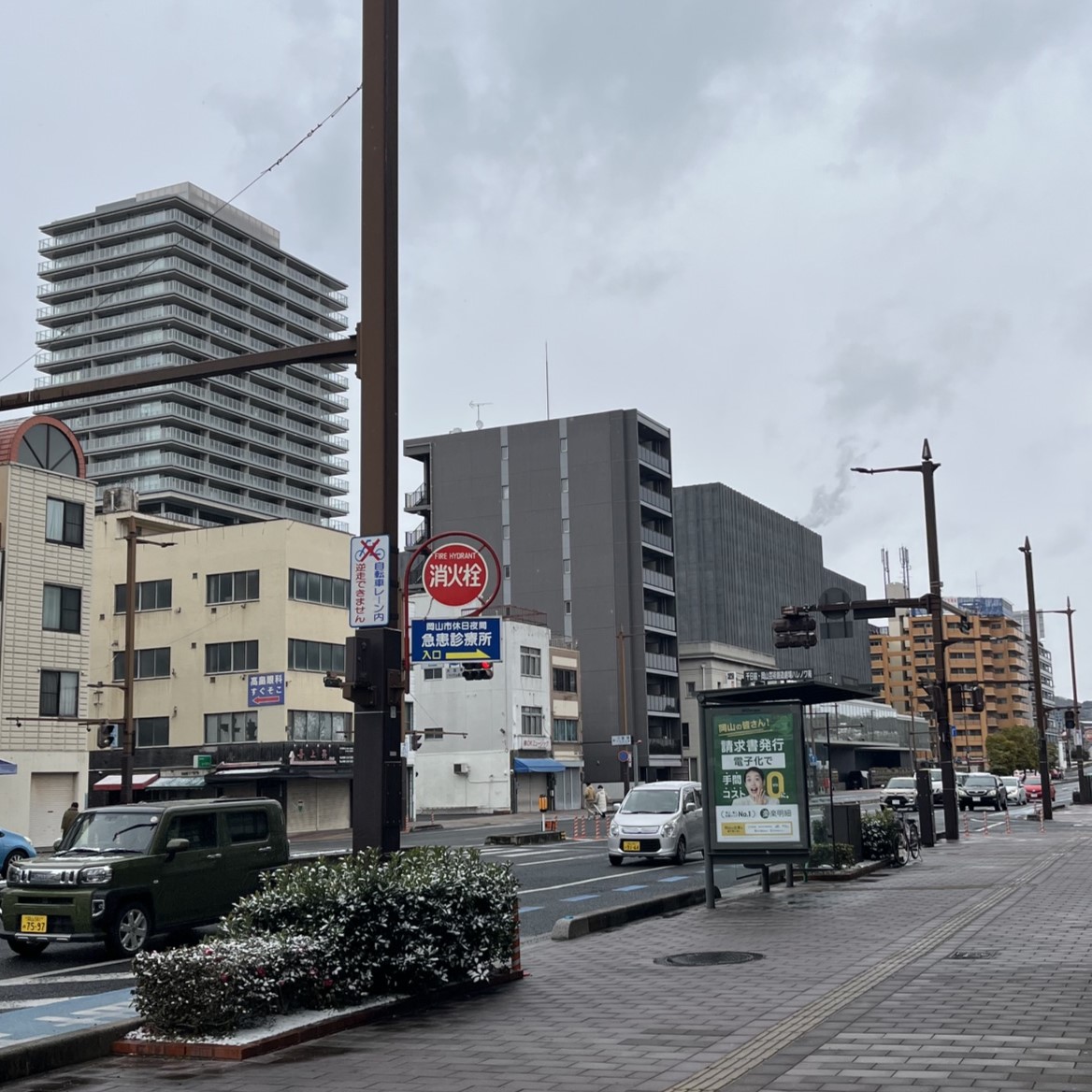 岡山市中心部、ビルやマンションが並び、道路の中央には路面電車の駅がある