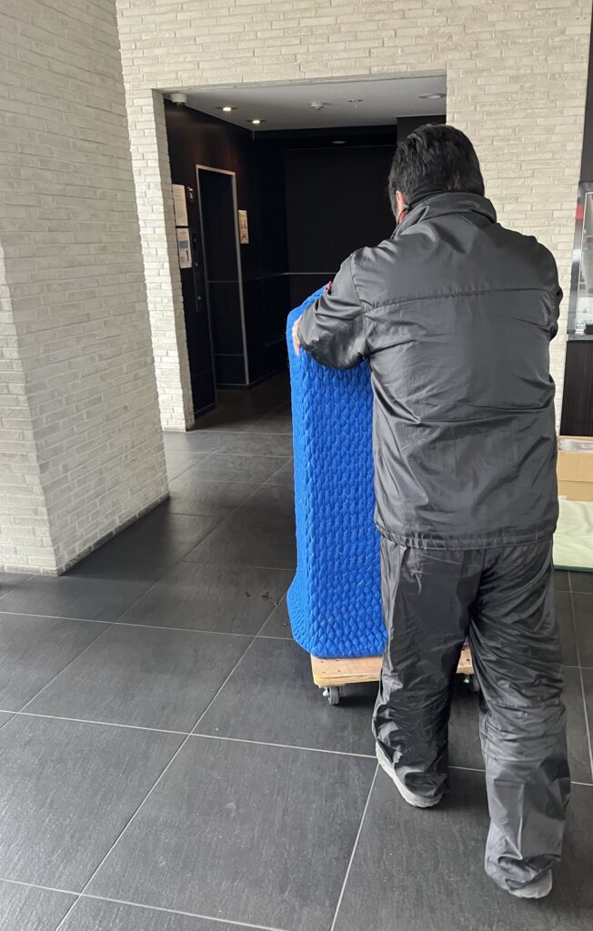 職人が安定した台車にお仏壇を乗せ、マンションの中を丁寧に運んでいる