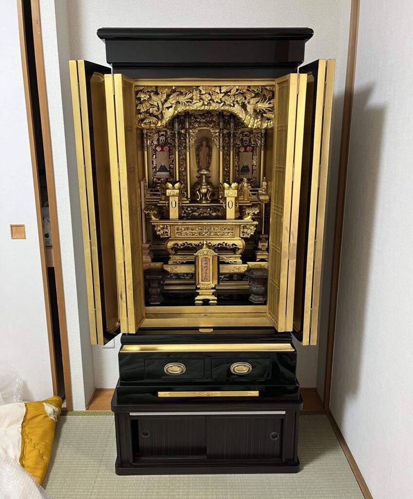 綺麗になったお仏壇に、仏具や装飾品を元々の場所にに戻して並べている