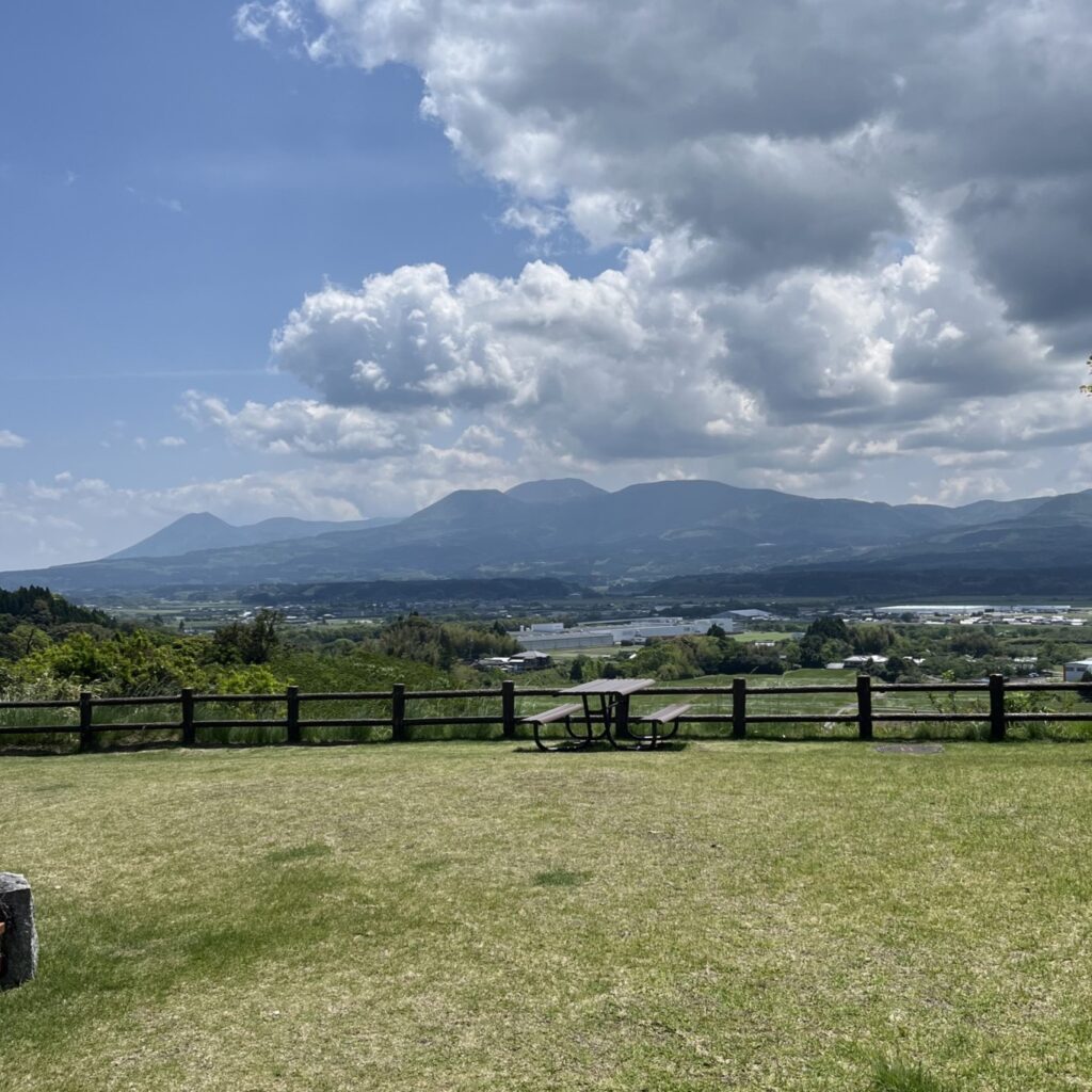 サービスエリアから見えるえびの高原、青空の元、なだらかな山に緑の高原が広がっている
